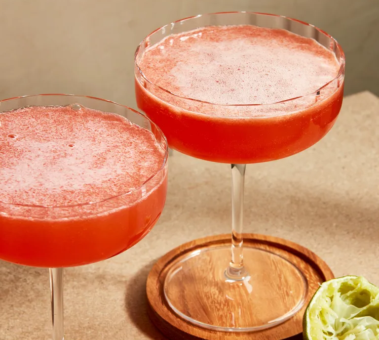 Cóctel Division Bell servido en copa de cóctel con piel de lima