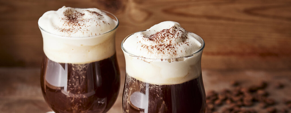 Irish Coffee servido en vaso resistente al calor, crema en la parte superior