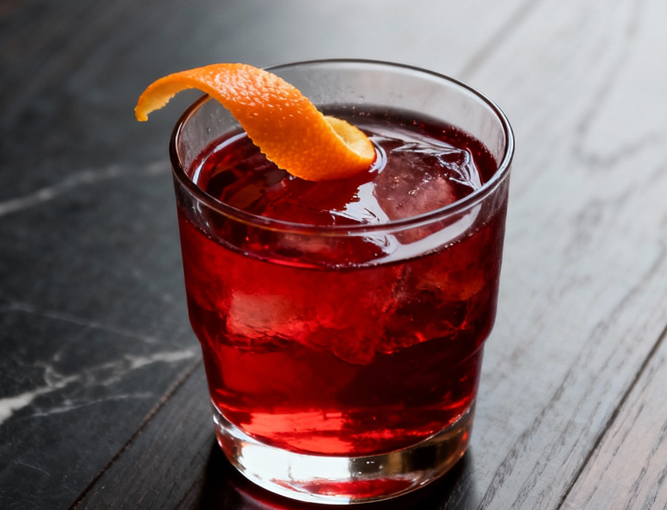 Negroni clásico italiano servido en vaso bajo con piel de naranja