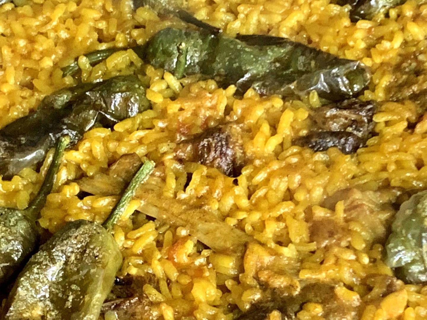 Paella de chuletas de cordero con tomate y pimientos del padrón