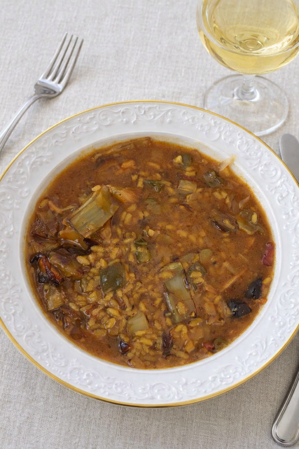 Arroz meloso con pulpo, alcachofas y verduras presentado en cazuela, con las rodajas de pulpo visibles y el arroz con textura sedosa