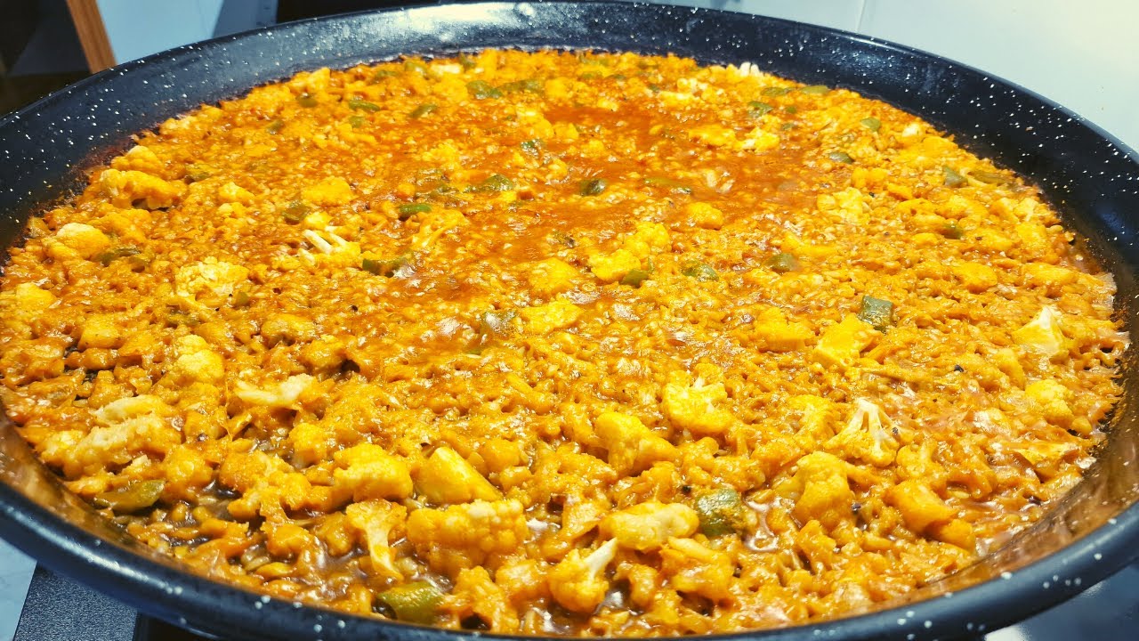 Paella de bacalao y col en paellera tradicional, mostrando el bacalao y la col bien integrados