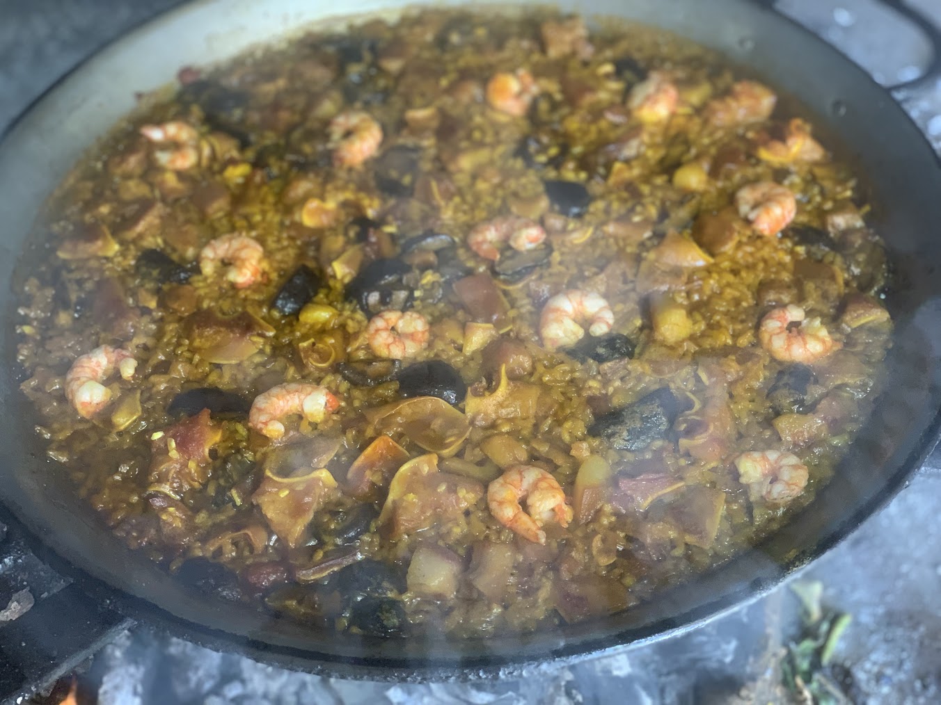 Paella de oreja de cerdo, boletus y gamba pelada mostrando la textura gelatinosa de la oreja y los boletus dorados