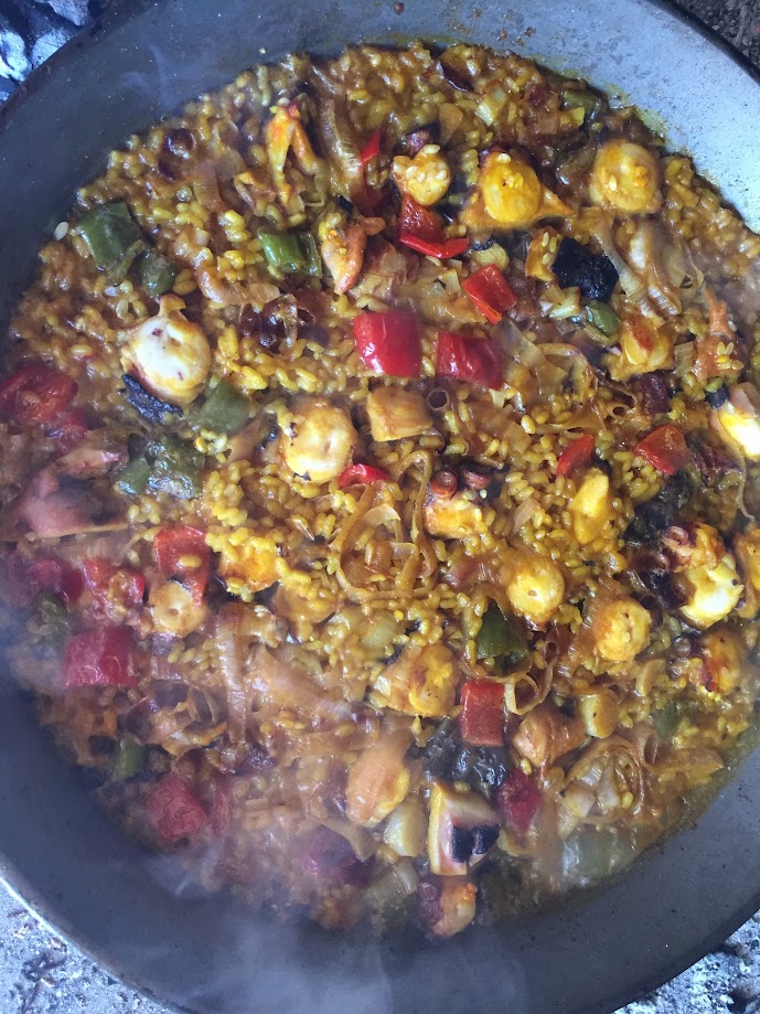 Paella de pulpo con ajos tiernos mostrando las ventosas del pulpo y el verde brillante de los ajos tiernos